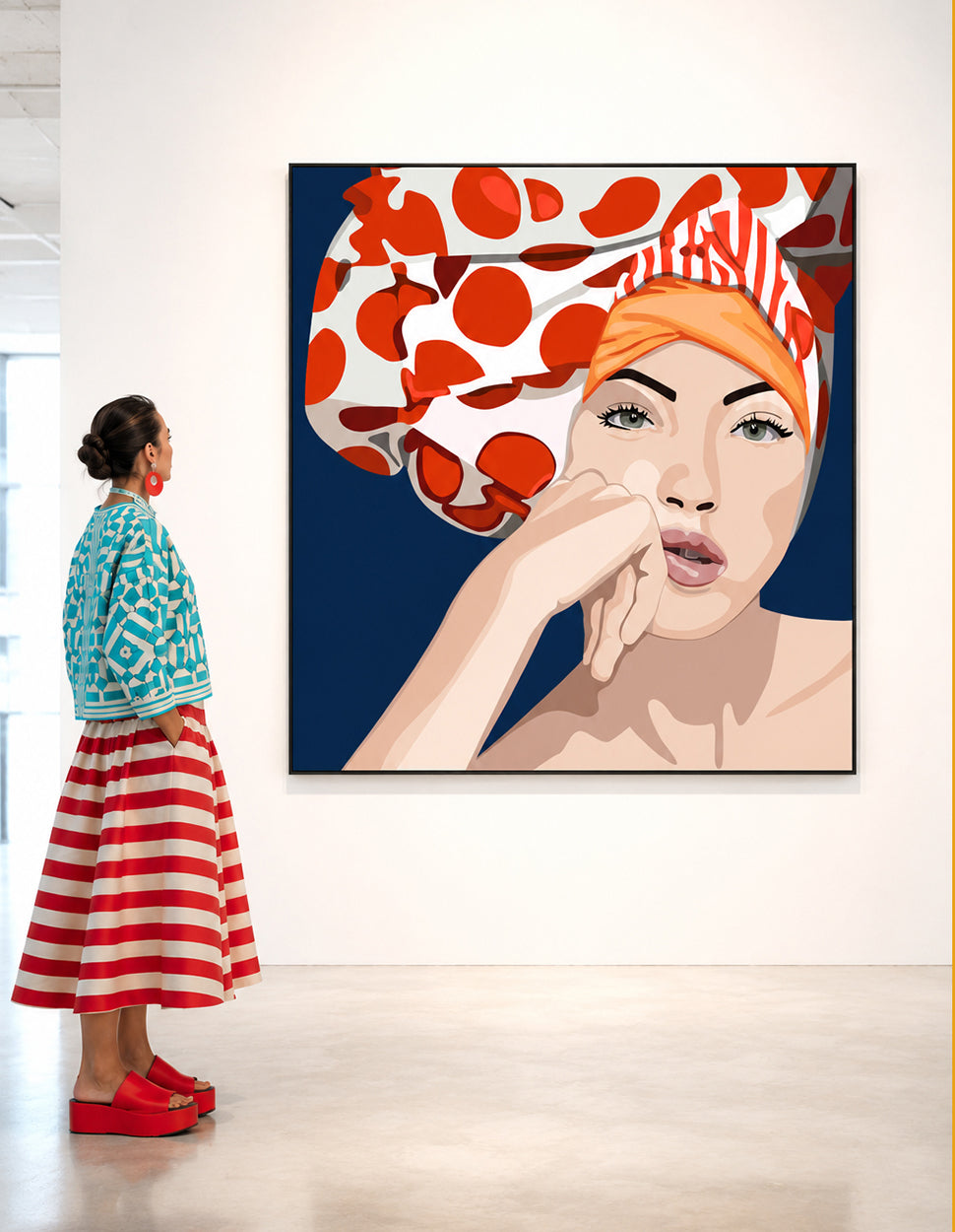 A woman in a turquoise patterned cardigan and red-and-white striped skirt stands in a gallery, looking at a large framed pop-art portrait painting of a woman wearing a red-and-white polka dot headscarf against a dark blue background. by Orit Fuchs