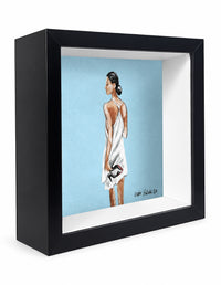 A framed art print in a black shadow box frame, featuring aoriginal painting by Orit Fuchs of a woman in profile wearing a white wrap dress against a light blue background.